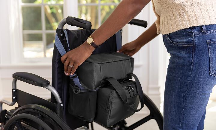 Woman attaching PureWick&trade; Portable Collection System in Carry Bag to wheelchair 