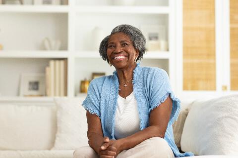 Daughter with arm around her senior citizen mother’s shoulder, both looking away and smiling