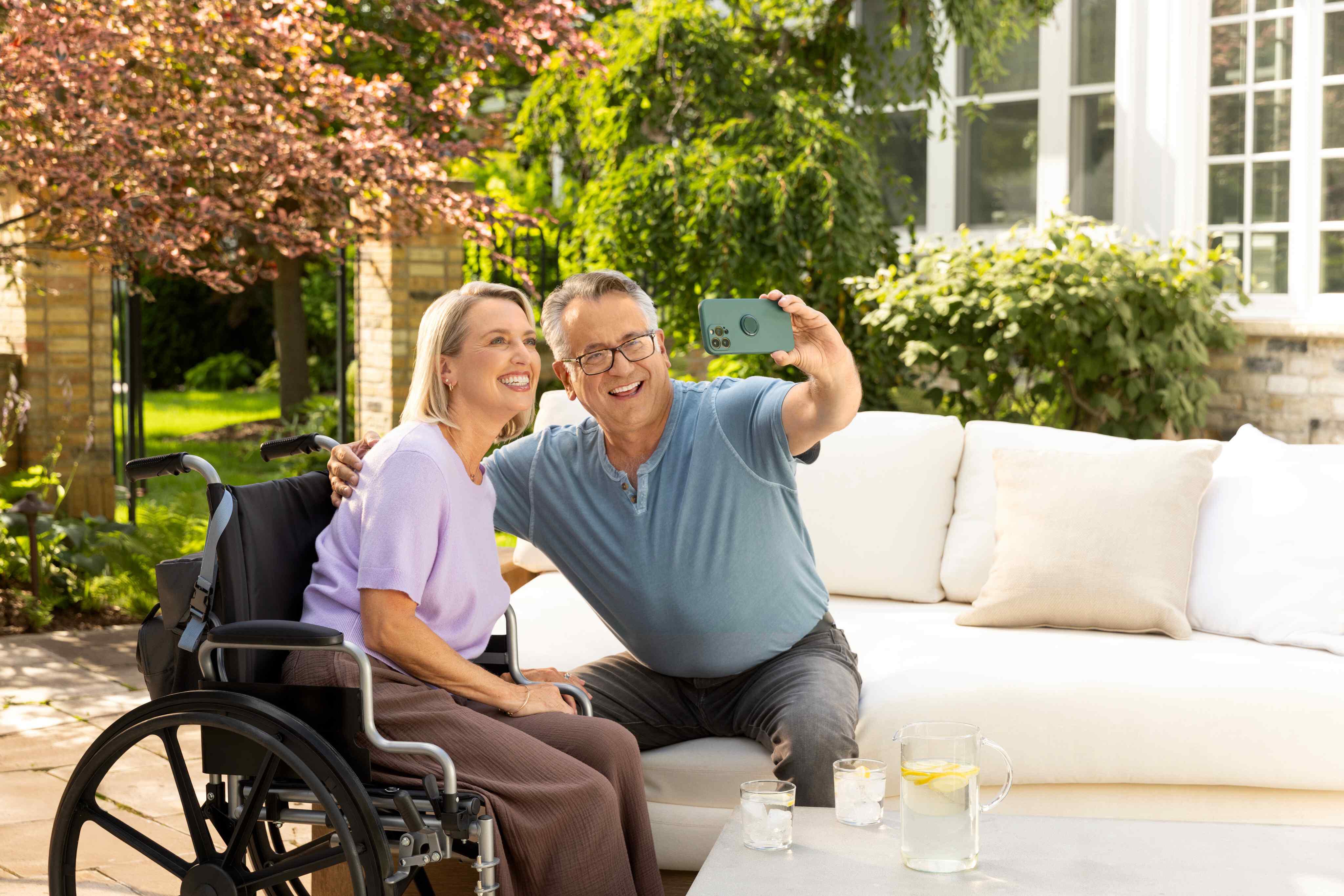 Woman in wheelchair with PureWickTM Portable Collection System and man on couch taking a selfie